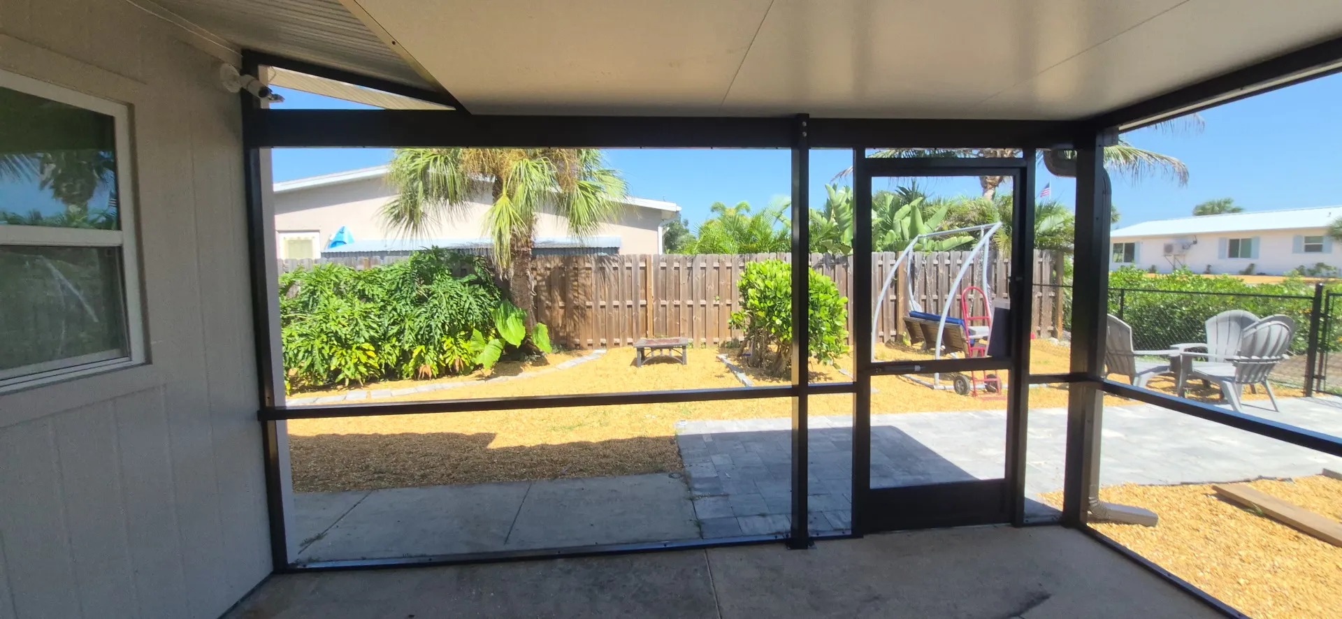 Interior view of a screened patio enclosure looking out to the backyard in Englewood, FL